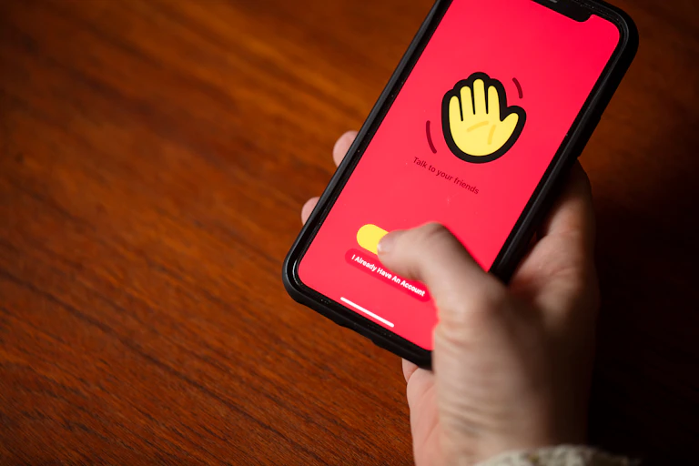 Una mano maneja un teléfono móvil con la aplicación House Party
