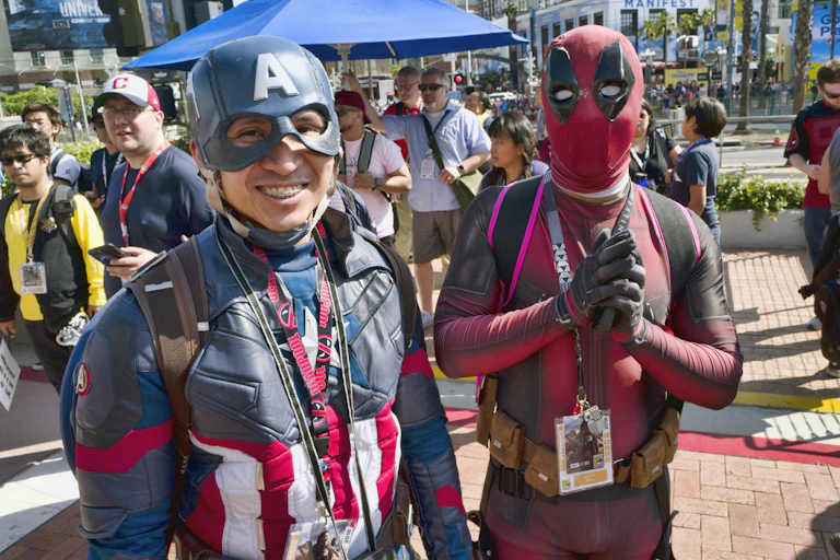 People dressed as Captain America and Deadpool stand in front of a crowd.
