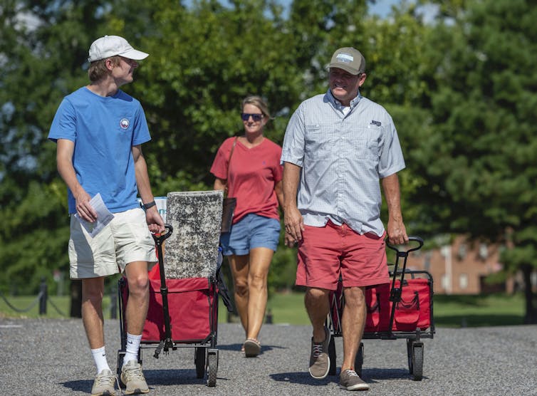 A freshman male walks with his parents toward his dorm.