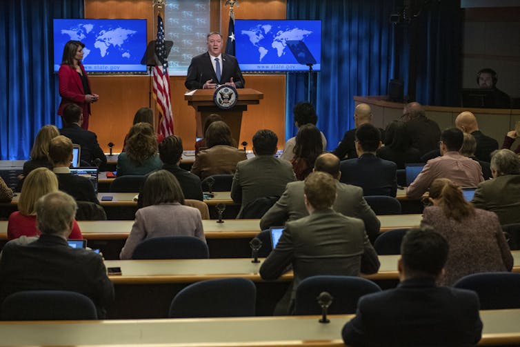 Pompeo, standing at the podium, speaks to seated reporters in the White House Press Briefing Room