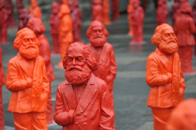 A crowd of red and orange plastic sculptures of Karl Marx