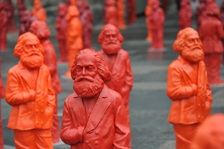 A crowd of red and orange plastic sculptures of Karl Marx