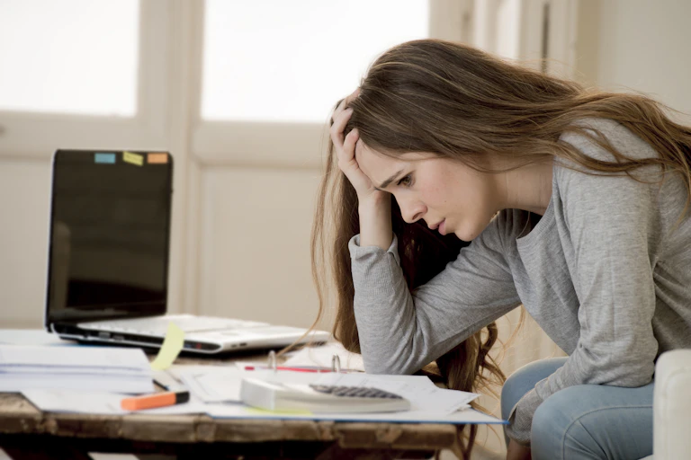 Young woman looking worried as she does her tax return