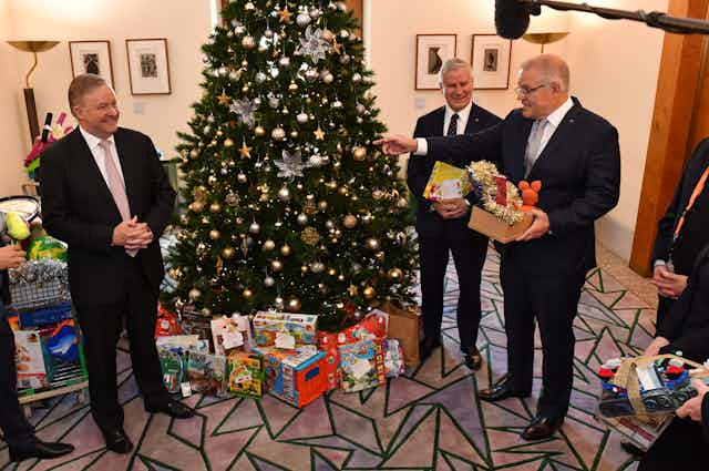 Anthony Albanese, Scott Morrison, and Michael McCormack, stand around a Christmas tree adorned in presents