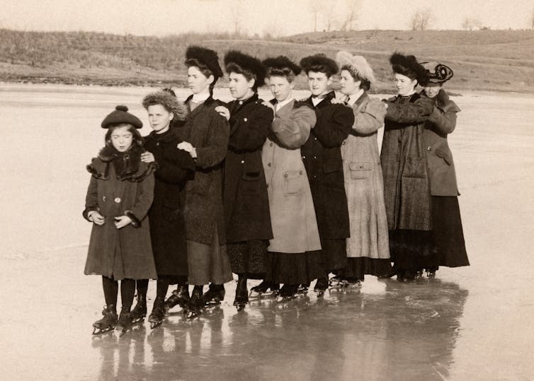 A line of Victorian women stand on a frozen lake.