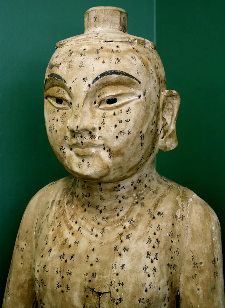 White statue of a man with Chinese characters drawn on.