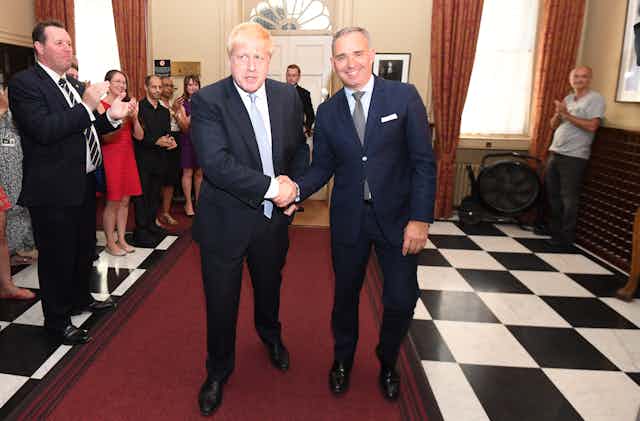 Boris Johnson shakes hands with his top civil servant. 