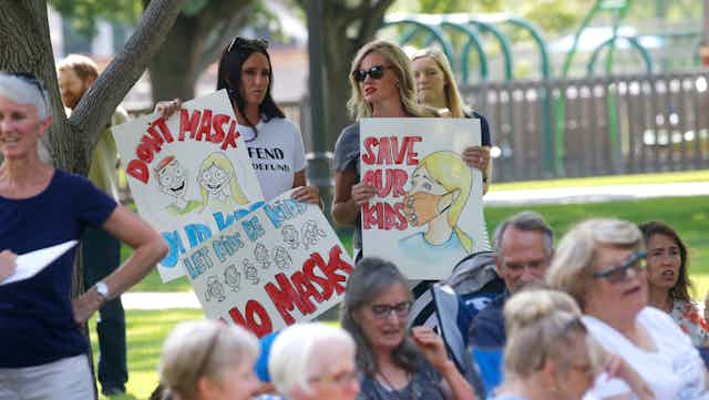 Two women hold anti-mask placards at a rally in Utah.