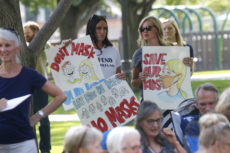 Two women hold anti-mask placards at a rally in Utah.