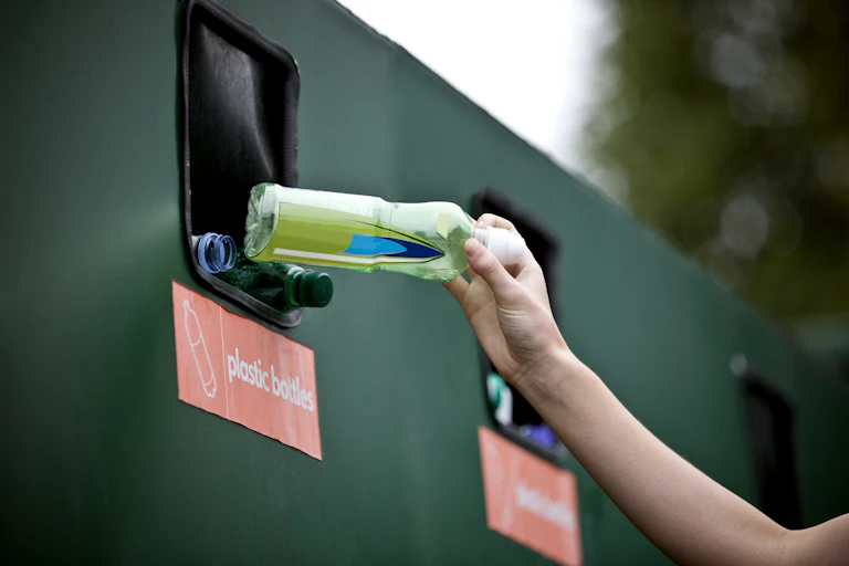 Someone depositing a plastic bottle in a bottle bank.