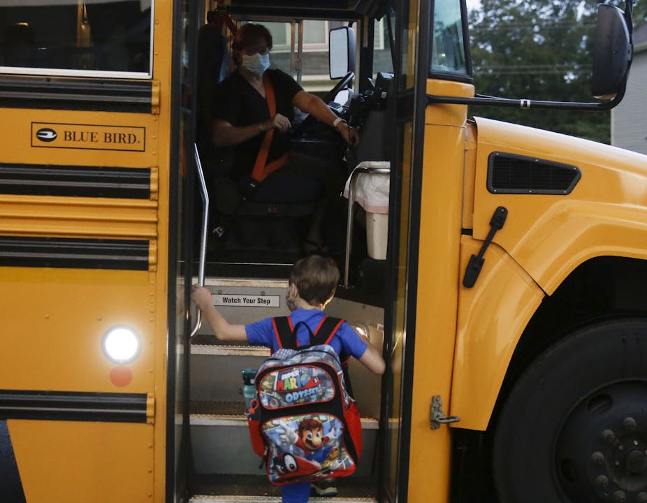 Paul Adamus, 7, climbs the stairs of a bus before the fist day of school on Monday, Aug. 3, 2020, in Dallas, Ga.