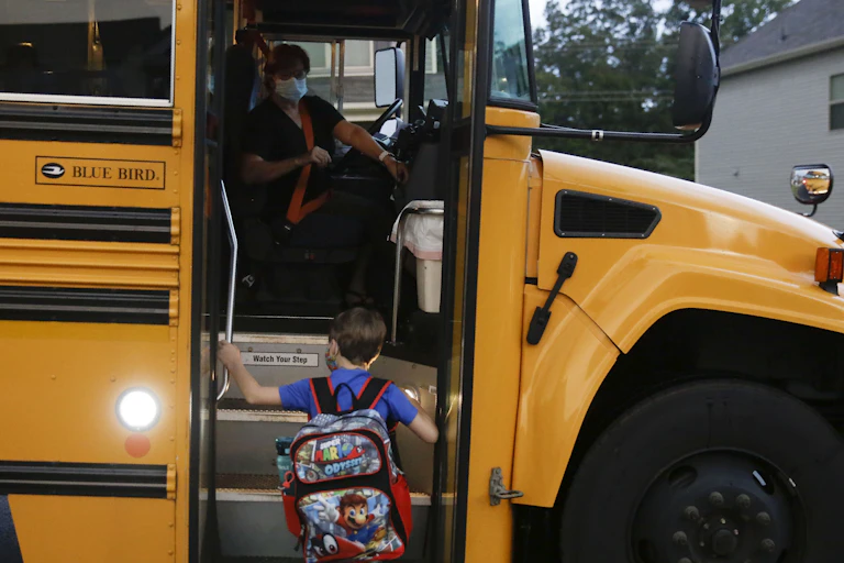 Paul Adamus, 7, climbs the stairs of a bus before the fist day of school on Monday, Aug. 3, 2020, in Dallas, Ga.