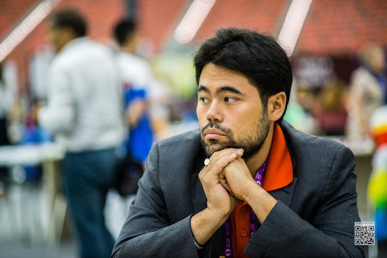 Hikaru Nakamura in suit at a chess tournament.