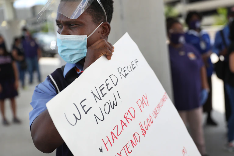 An unemployed airline worker holds a sign calling for an extension of federal benefits.