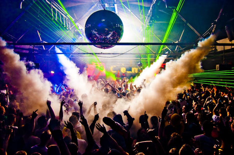Nightclub, with disco ball, smoke machine and people dancing.