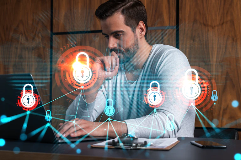 Man at desk looking at laptop, overlaid with network of padlocks