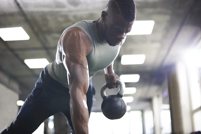 A muscular man working out with weights in a gym