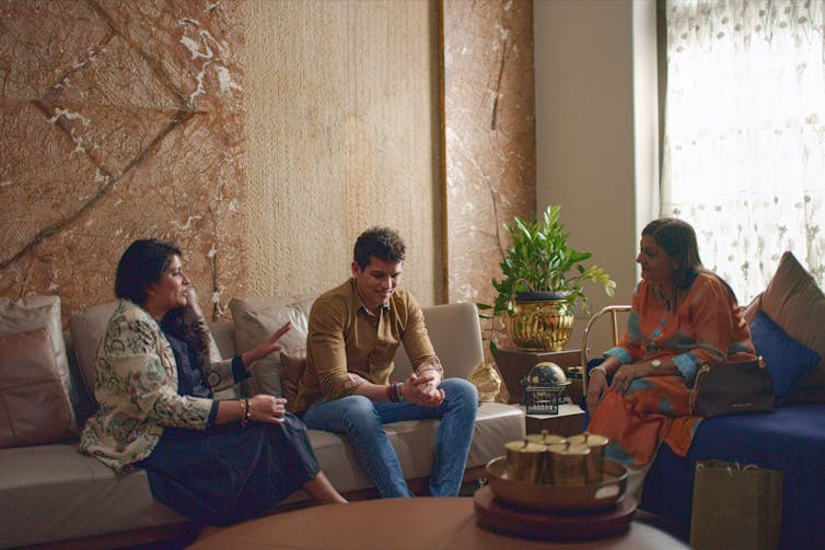 Three people sitting on sofas.