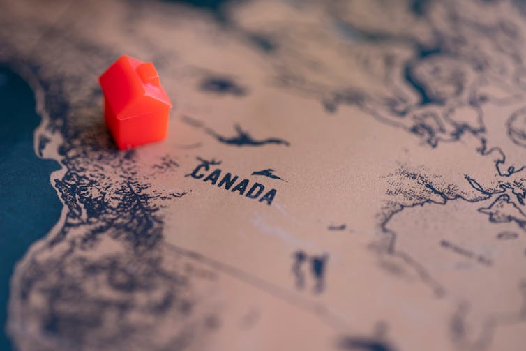 a red monopoly house placed on a map of Canada.