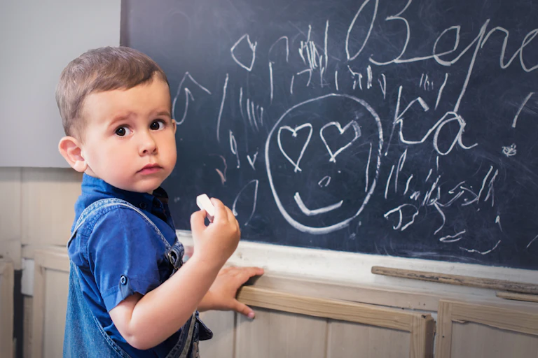 Niño con cara de susto ante una pizarra emborronada,