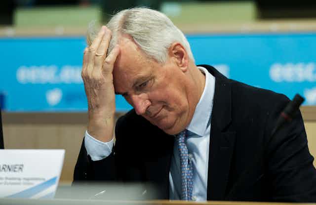 Michel Barnier holding his head with his hand.