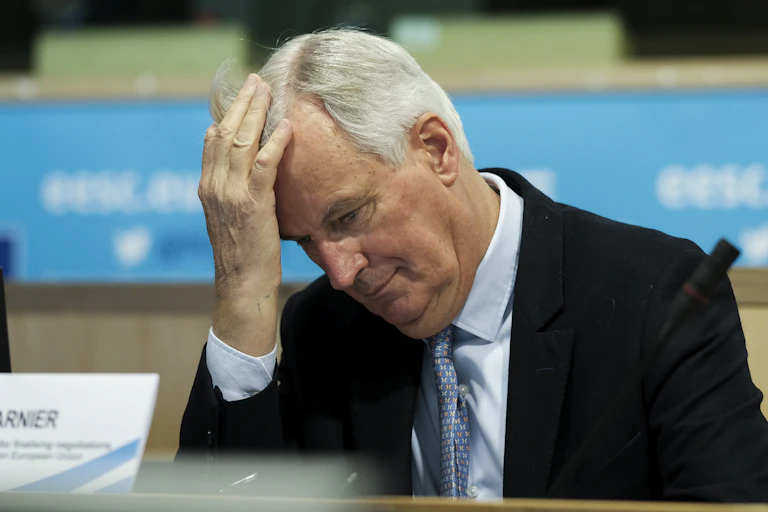 Michel Barnier holding his head with his hand.