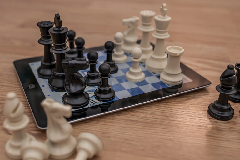 Chess pieces sitting on an iPad displaying a chess board.