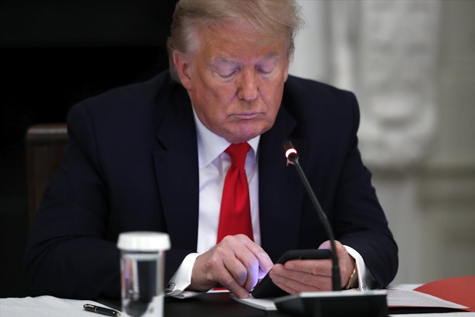 Donald Trump looks at a smartphone