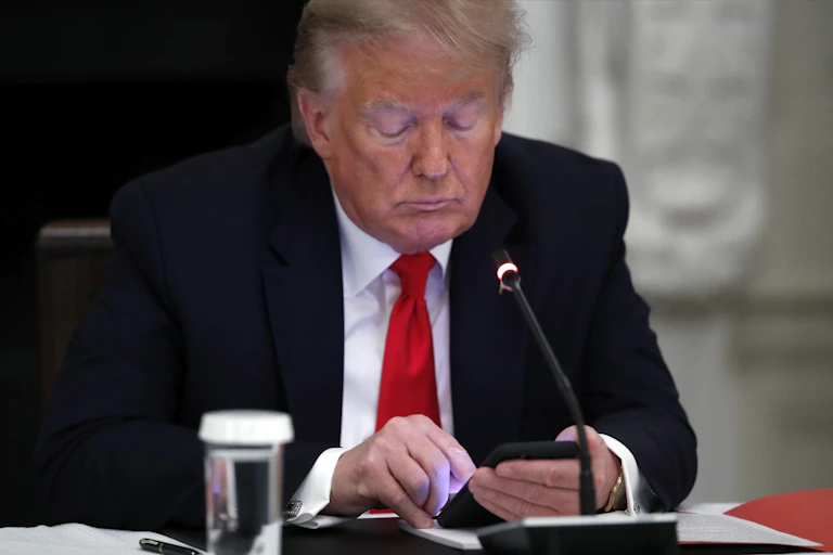 Donald Trump looks at a smartphone