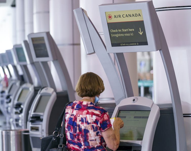 A woman uses an Air Canada self-service kiosk.