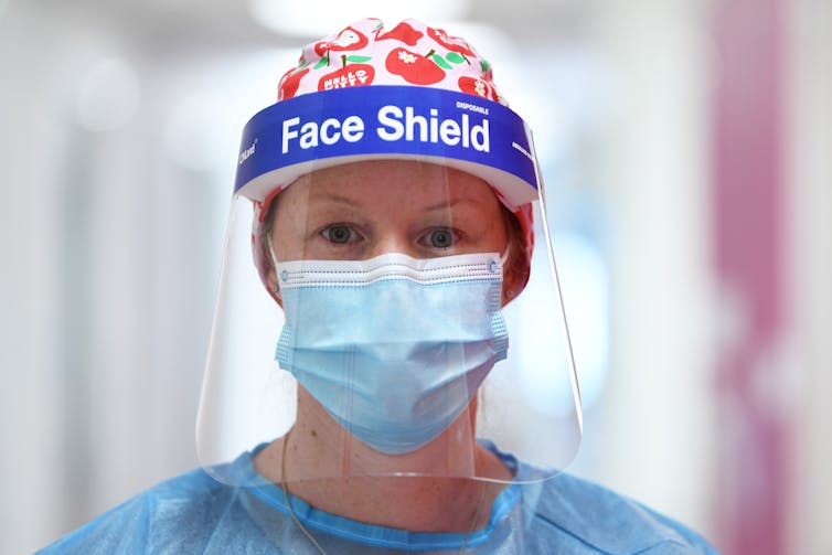 A woman in a face-shield and a mask.