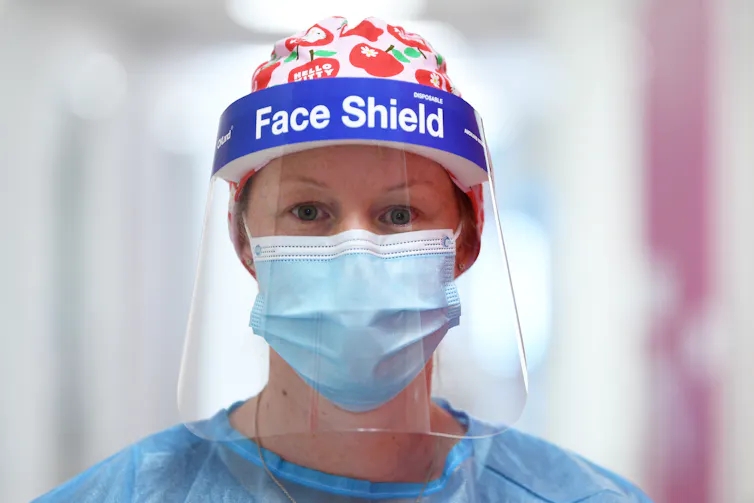 A woman in a face-shield and a mask.