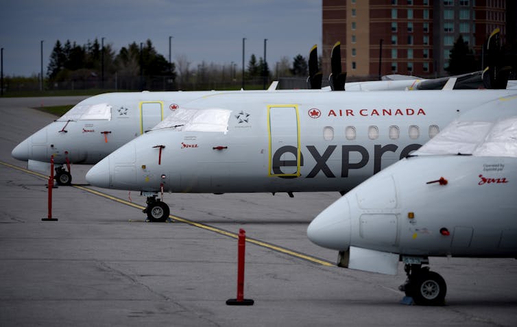 Air Canada Express aircraft sit on a tarmac with covered windshields.