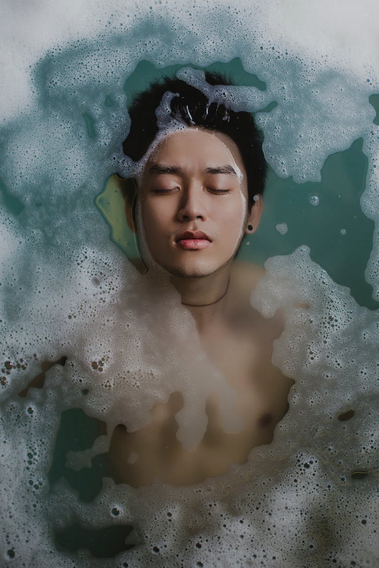 A man floats in a bath.