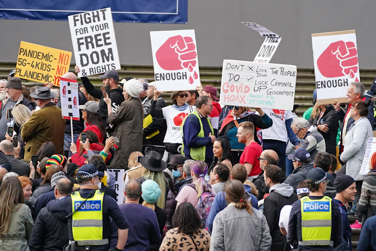 Crowd of anti-lockdown protesters with signs and police