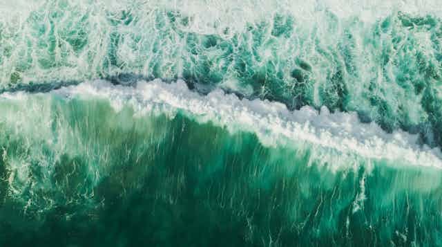 Una ola rompiente en aguas color turquesa.