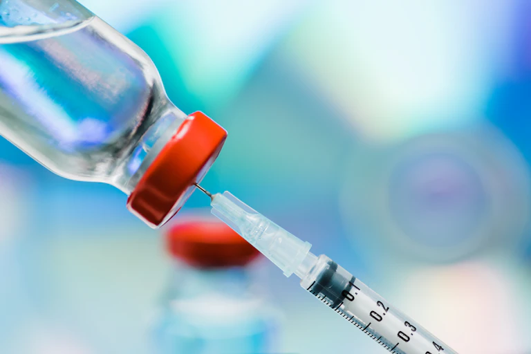 Vaccination vial with syringe attached.