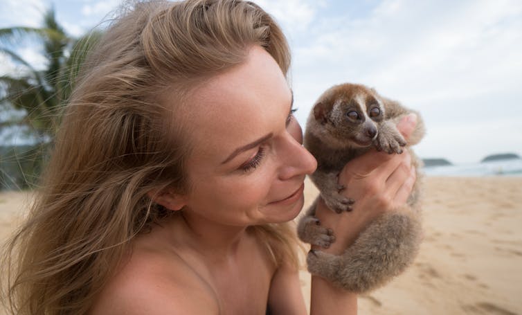 Woman on beach holds cute primate.