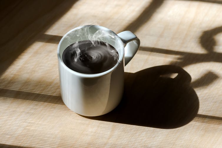Steaming coffee cup on table.
