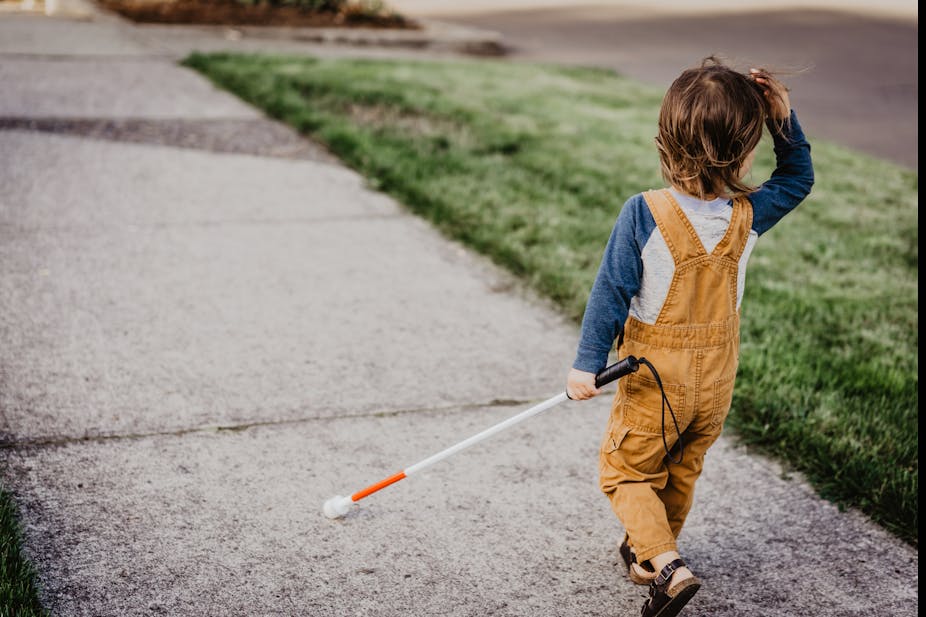 Blind child walking with cane.