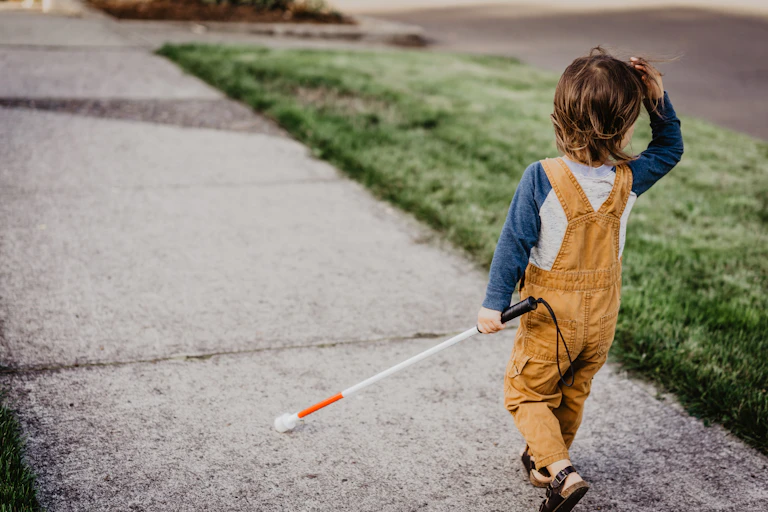 Blind child walking with cane.