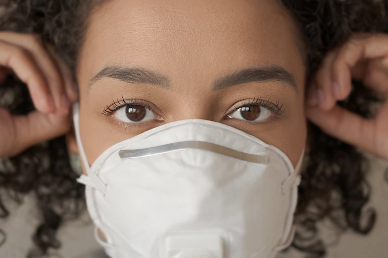 Mujer de otros grandes y marrones con mascarilla.