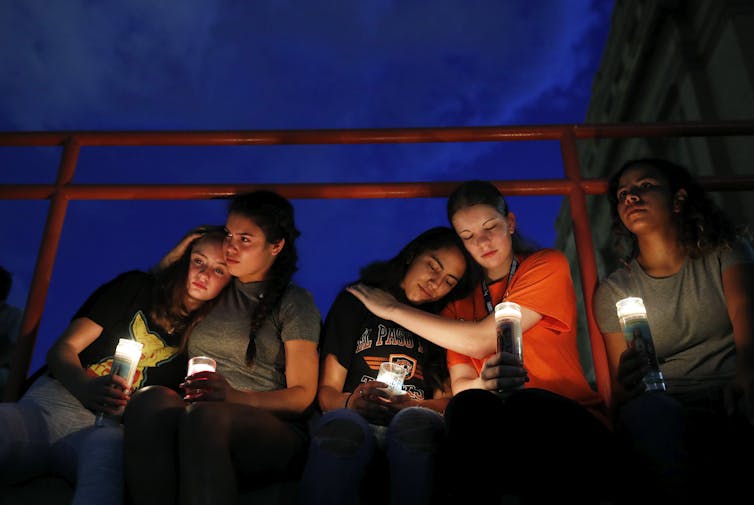 People hug each other and hold candles at a vigil