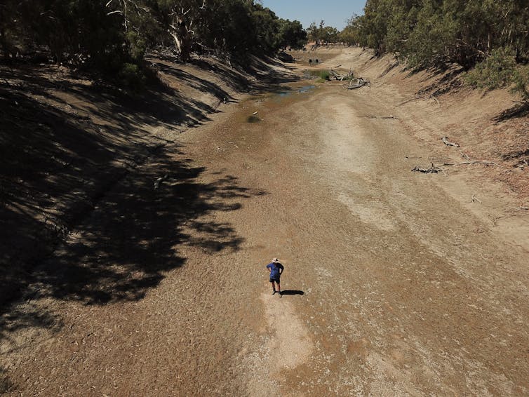 A farmer stands in the dry river bed of the Darling River