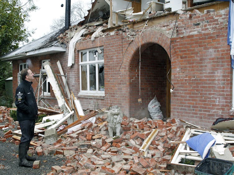 A man stands before a pile of rubble.