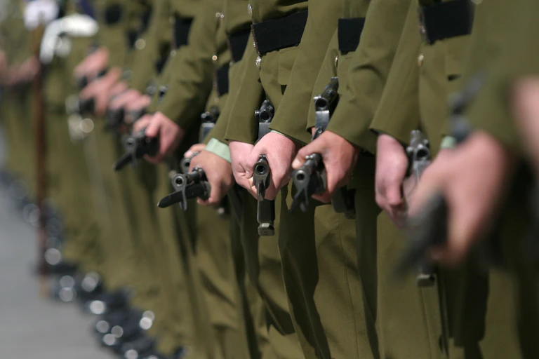 A line up of soldiers holding their guns with bayonets in place.