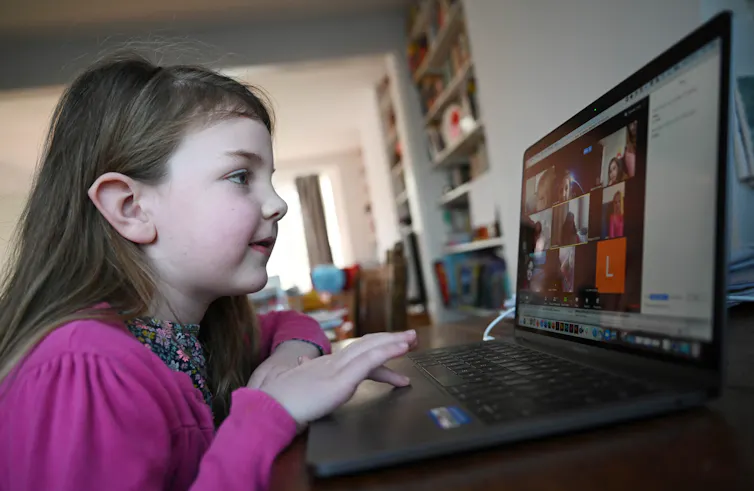 A young girl at home using a laptop.