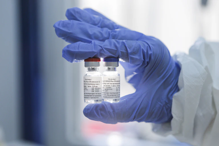 Gloved hand holding two phials of coronavirus vaccine
