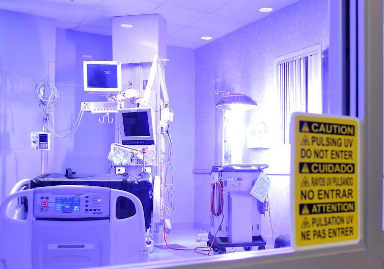 a robot emitting ultraviolet light in an empty hospital room