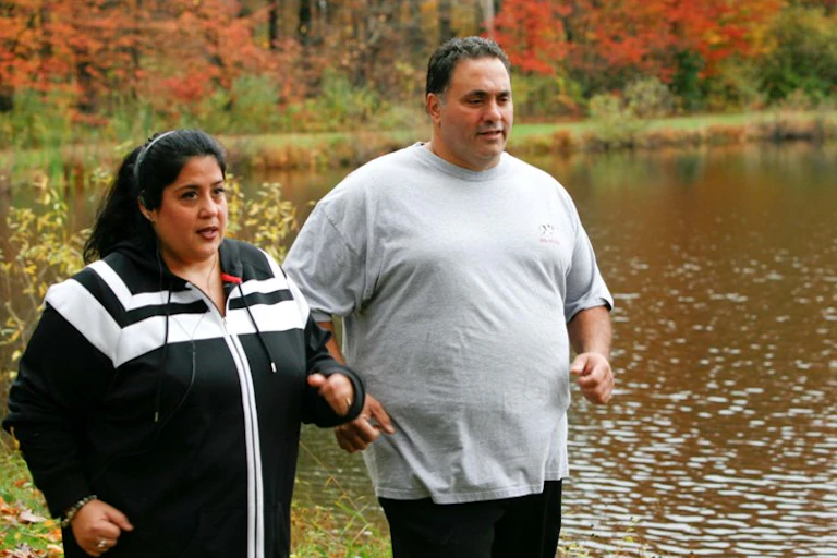 A ma and woman walk by a lake.